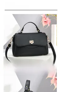 Detail of black litchi grain leather bag with gold shield-shaped metal buckle lock