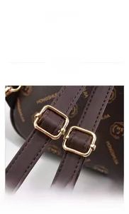 Detail view of adjustable backpack straps with gold metal buckles on brown floral leather