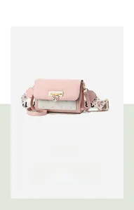 Detail of pink and white crossbody bag featuring heart-shaped lock and floral strap
