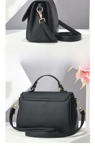 Detail of black pebbled leather texture and gold metal hardware on crossbody bag