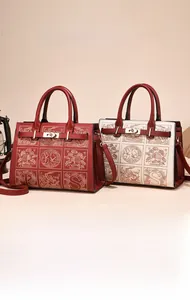 Detail of red and cream leather tote bags with floral patterns and gold twist-lock closure