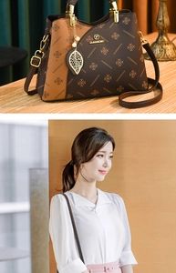 Close-up of brown patterned handbag with gold circular handle and leaf charm detail