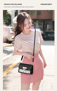 Outdoor shot of a small black and white crossbody bag with a gold heart clasp