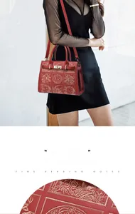 Detail of red tote bag with intricate bird floral embroidery and golden metal clasp