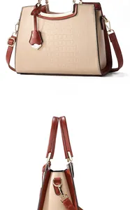 Detail view of contrast color handbag with crocodile texture and gold metal handle