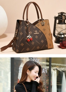Detail of retro vintage patterned tote bag with cherry charm and leather handle detail