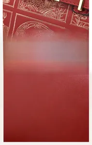 Detail of red PU leather handbag with gold embroidery and lychee grain texture