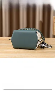 Detail view of the contrasting colors, woven handle, and bottom metal studs of the green bag