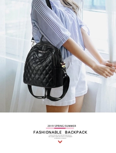 Detail of black quilted leather backpack with stylish charm and metal zipper closure