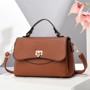 Brown litchi grain leather crossbody bag with gold U-shaped metal lock on a display stand