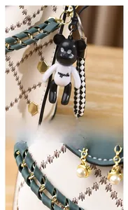 Detail of crossbody bag with diamond embroidery, gold rivets, and a bear charm