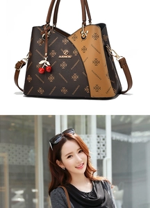 Detail of vintage monogrammed brown handbag featuring cherry charm and golden hardware