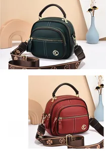 Close-up of textured leather crossbody bag with multiple zippers and wide woven strap