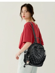Detail of black quilted leather backpack with hello charm shown on model