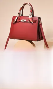 Detail of red large capacity handbag with silk scarf handle and metal lock