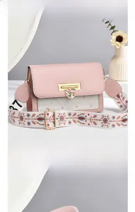 Close-up of pink and white crossbody bag featuring golden heart relief and floral strap