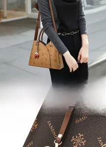 Detail of Janenovo brown faux leather tote with floral pattern and cherry charm accessory