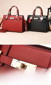 Detail of red leather handbag showing gold metal buckle and printed silk handle scarf