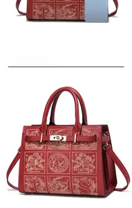 Close-up of red leather handbag featuring gold embroidery and metallic twist lock clasp