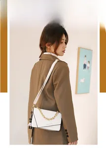 Chic white crossbody bag with gold chain strap and cute bear charm shown on model
