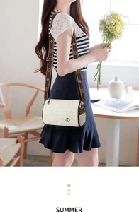 Detail of cream crocodile pattern cylinder bag with clover logo and jacquard strap