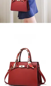 Detailed view of red leather handbag with silk scarf handle and metal twist lock