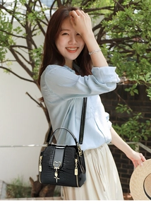 Detail of black crocodile texture bucket bag with gold heart lock and star pendant