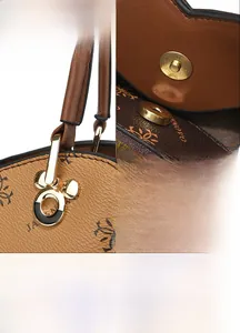 Detail view of gold metal buckles and refined stitching on a brown leather handbag