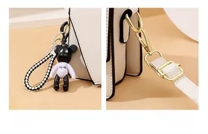 Detail of cream leather handbag with fashion bear pendant and golden hardware hooks