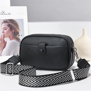 Black pebbled leather crossbody bag with three zip layers and wide geometric strap