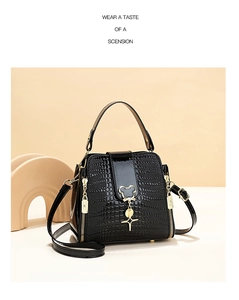 Close-up of black crocodile-embossed patent leather bucket bag with gold accents