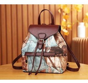 Close-up of vintage denim pattern and brown leather details on a multi-pocket backpack