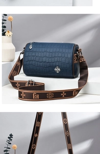 Detail of navy crocodile texture cylinder bag with floral woven shoulder strap
