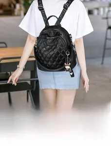 Close-up of black quilted backpack featuring a cow charm and detailed zipper compartments