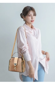 Brown crocodile pattern bucket bag with golden buckle shown on a crossbody model
