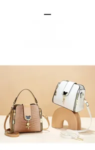Detail of crocodile pattern leather bucket bag with metal charms and shoulder strap