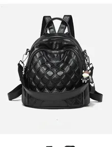 Front detail of black quilted faux leather backpack with cartoon keychain and gold zippers
