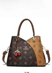 Detail of retro tote bag with dual-tone monogram pattern and cherry pendant charm