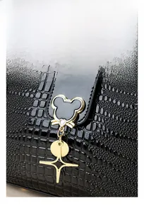 Detail of gold metal lock with heart rhinestone and star charms on black croc handbag