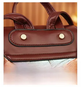 Close-up of reinforced stitching and gold rivet details on vintage brown patterned backpack