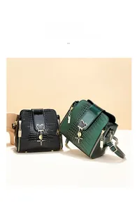 Detailed view of crocodile pattern leather handbags in black and dark green with bear charm
