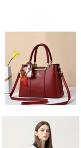 Detail of red faux leather handbag with gold hardware and printed silk scarf accessory