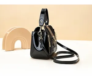 Side view of black crocodile pattern bucket bag with polished finish and metal zipper