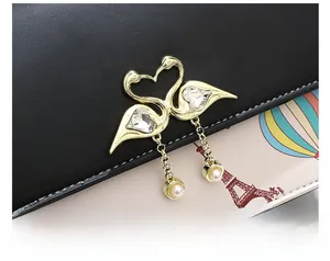 Detalle de elegante bolso de cuero blanco y negro con herraje de cisne dorado y perla