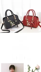 Detailed embroidery on leather handbag with a butterfly charm and top handle