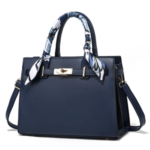 Elegant navy blue leather handbag with gold hardware and stylish patterned silk scarf wrap
