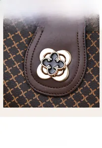 Detail of four-leaf clover metal lock and stitching on a grey leather crossbody bag
