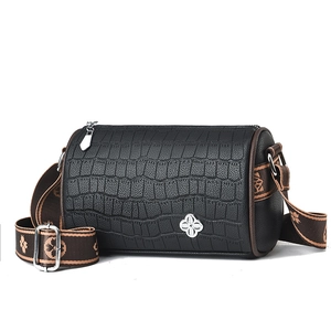 Black crocodile pattern cylinder crossbody bag with floral strap on white background