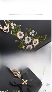 Detail of multi-color floral embroidery and petal charm on black leather handbag