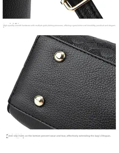 Detail of gold metal buckle and protective studs on black crossgrain leather tote bag